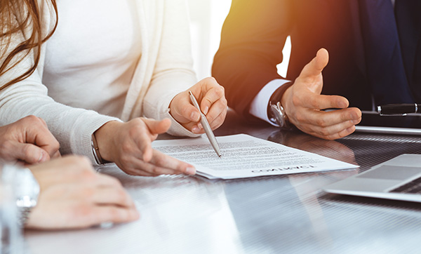 people discussing a document with a pen on a table including a laptop showing collaboration strategies for business growth such as 11 key points